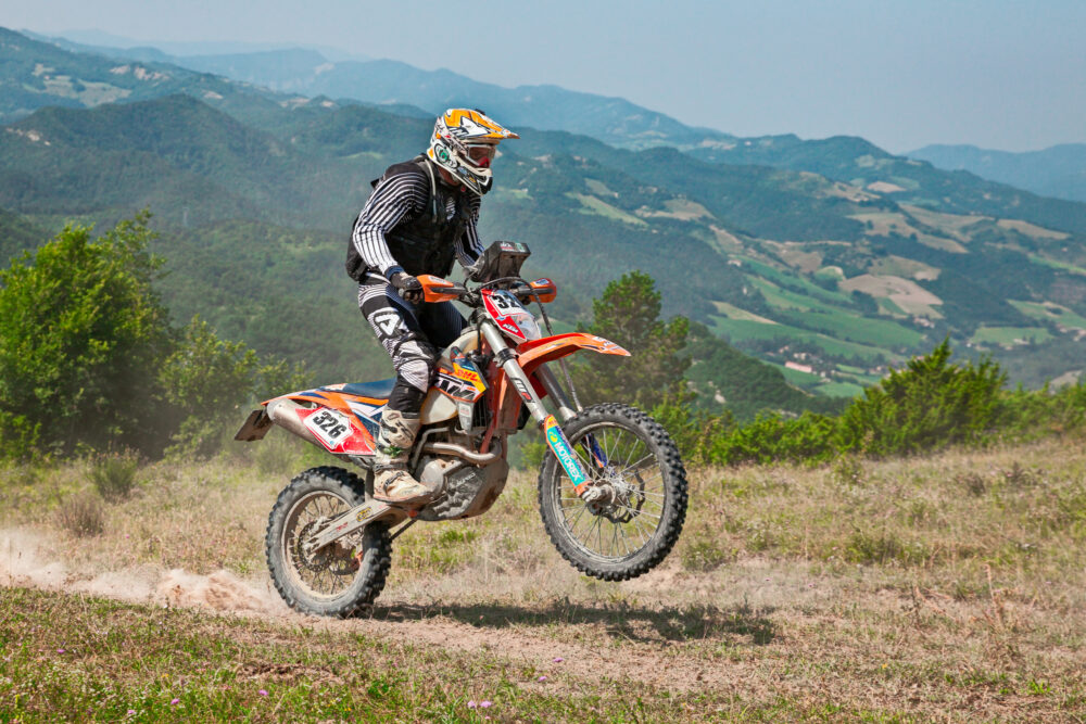 Biker riding enduro motorcycles KTM 450 EXC in the green hills during the Italian championship